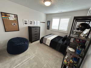 Bedroom with light carpet and a textured ceiling