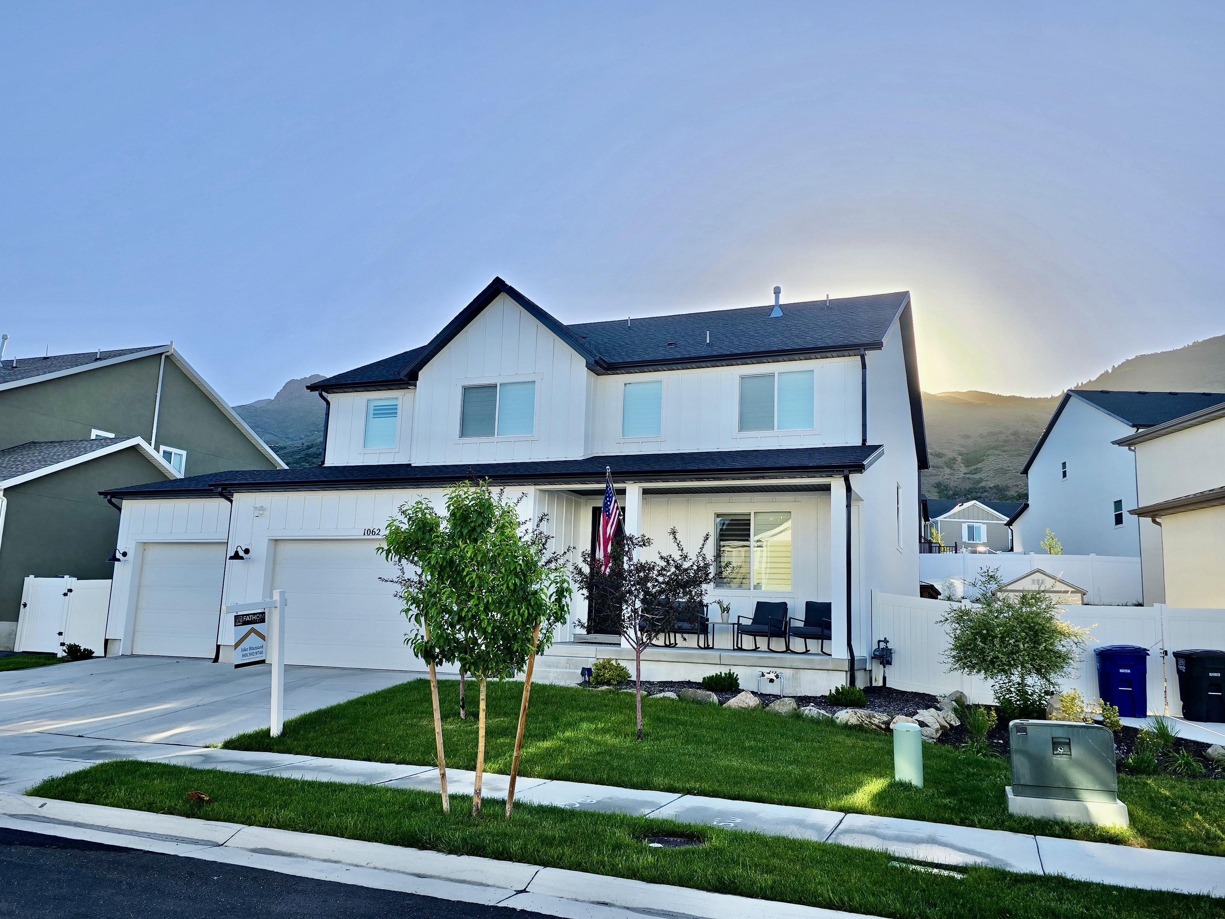 Modern two-story residence featuring a black and white exterior, a three-car garage, and a covered front porch
