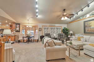 Living room with vaulted ceiling, light carpet, ceiling fan, and suspended lighting