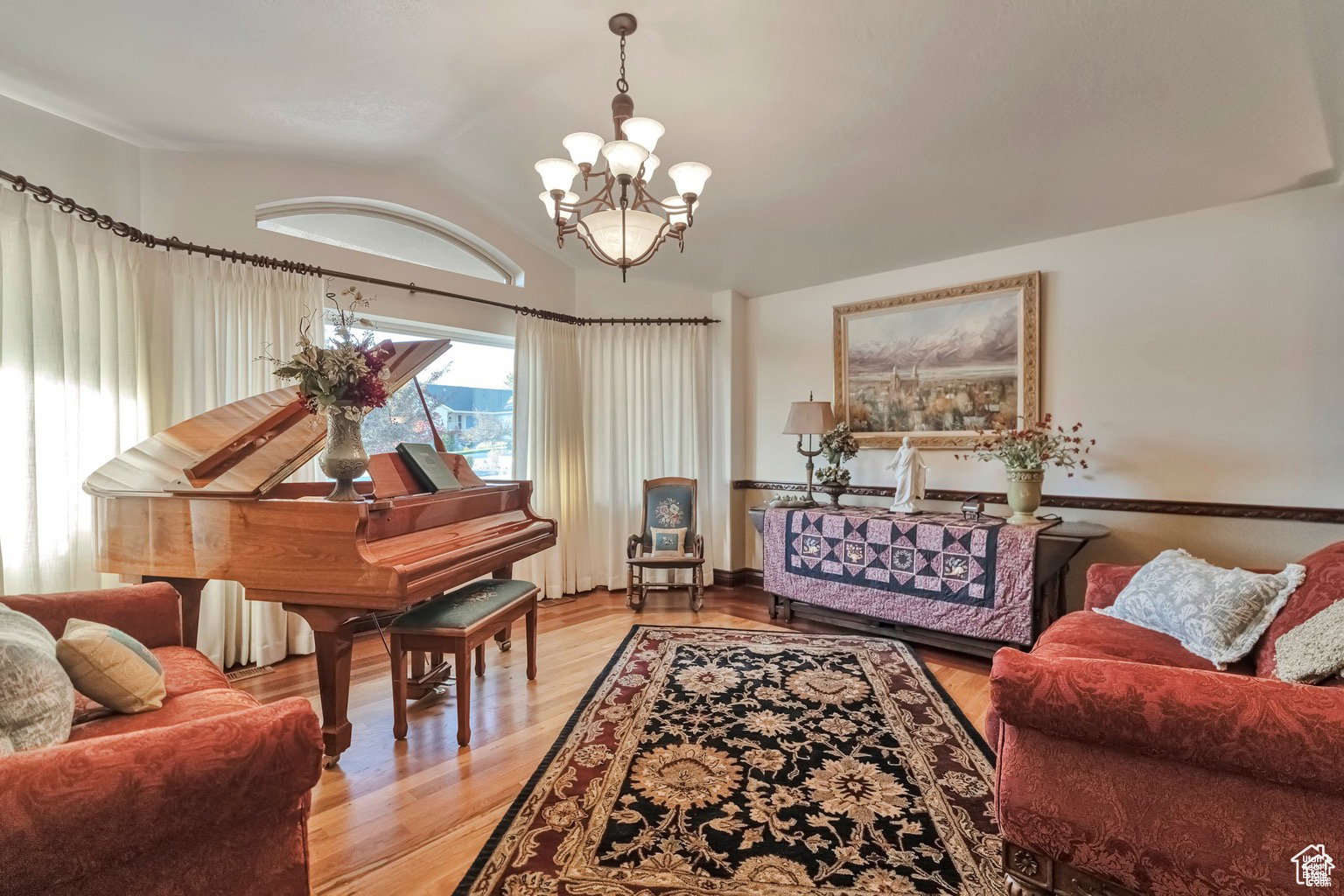 Sitting room featuring light wood finished floors, suspended lighting, and vaulted ceiling