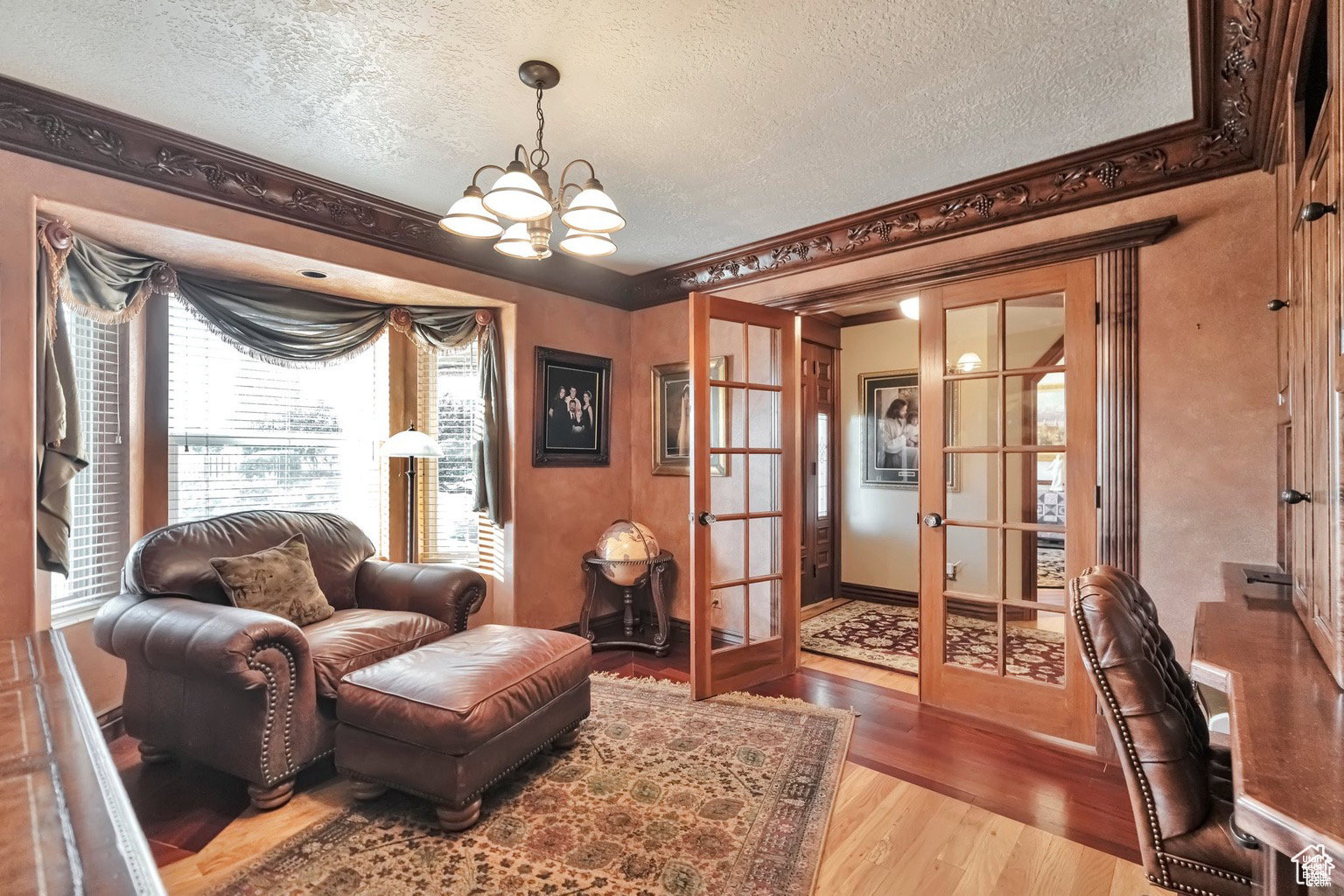 Living area with french doors, wood finished floors, a textured ceiling, and suspended lighting