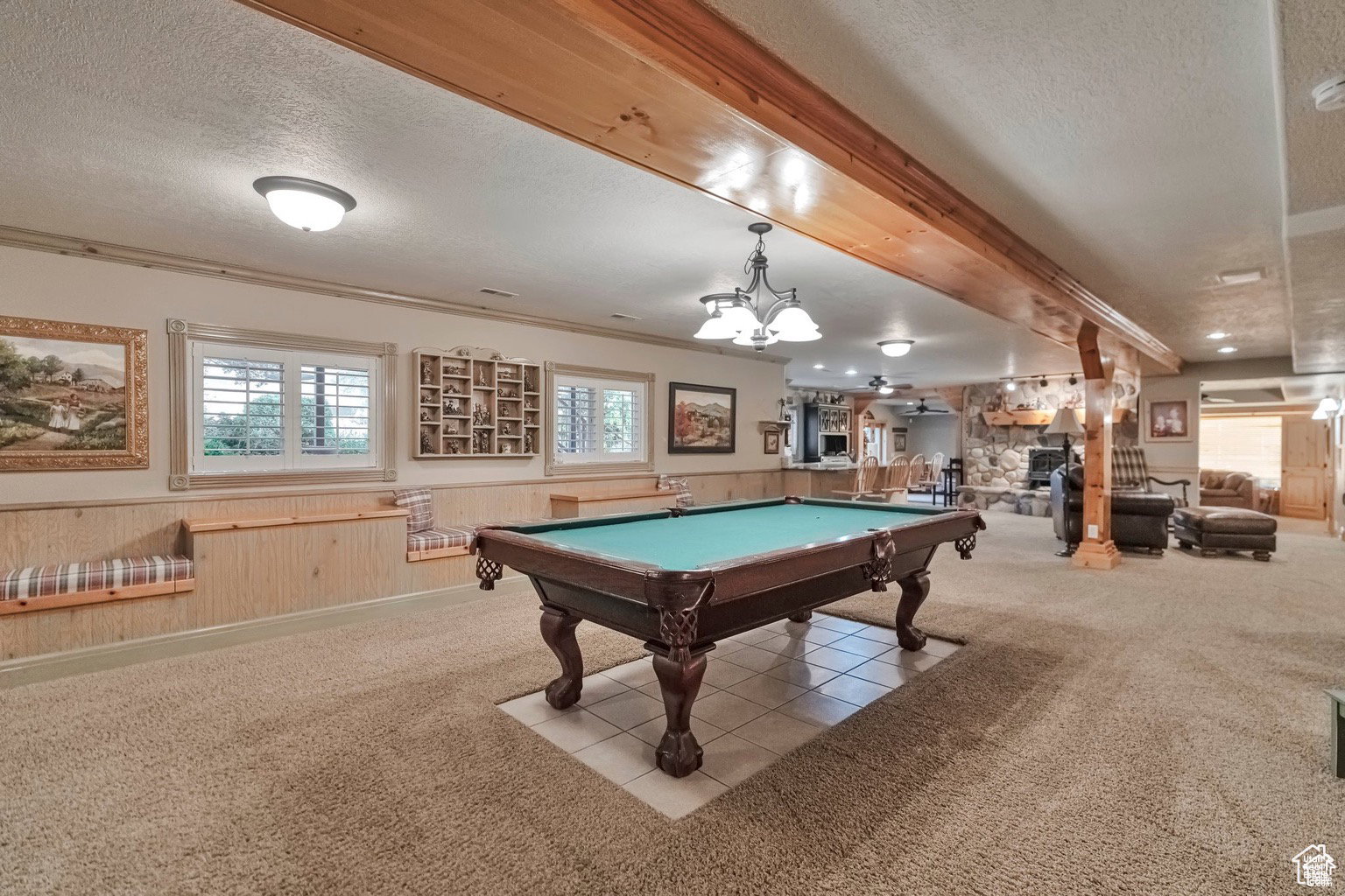 Playroom with wainscoting, a textured ceiling, wooden walls, carpet flooring, and a stone fireplace