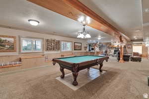 Playroom with wainscoting, a textured ceiling, wooden walls, carpet flooring, and a stone fireplace