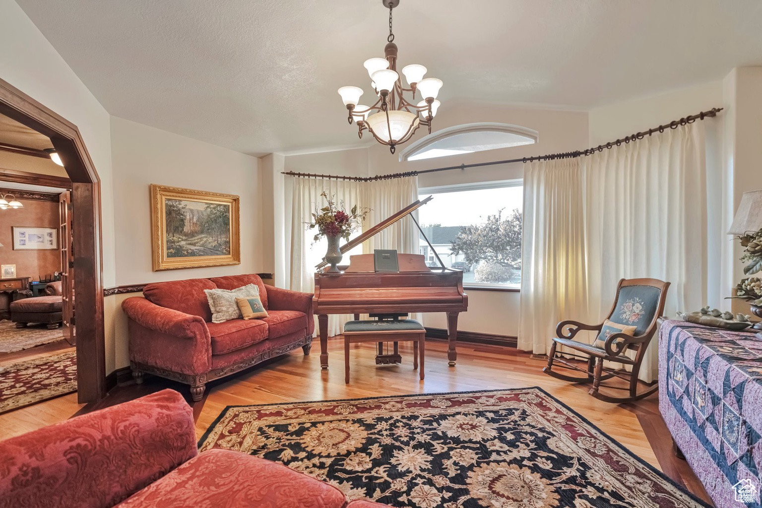 Sitting room with suspended lighting and light wood-style flooring