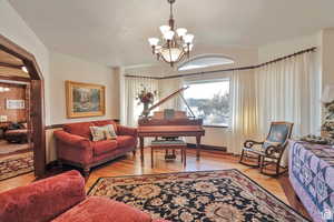 Sitting room with suspended lighting and light wood-style flooring