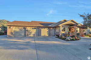 View of front facade featuring an attached garage, driveway, roof with shingles, and brick siding