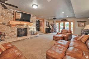 Carpeted living room with a ceiling fan, a textured ceiling, french doors, a fireplace, and recessed lighting