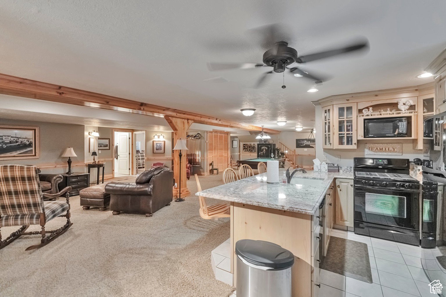 Kitchen featuring black appliances, a peninsula, light stone counters, a kitchen breakfast bar, and open floor plan