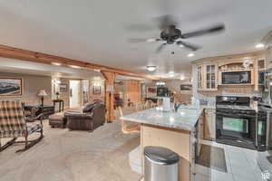 Kitchen featuring black appliances, a peninsula, light stone counters, a kitchen breakfast bar, and open floor plan