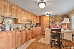 Kitchen featuring light wood finish cabinets, a breakfast bar, and light stone counters