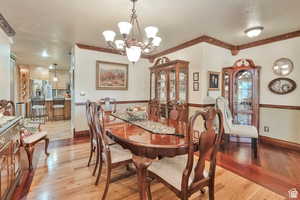 Dining area with light wood-type flooring, a chandelier, and a textured ceiling