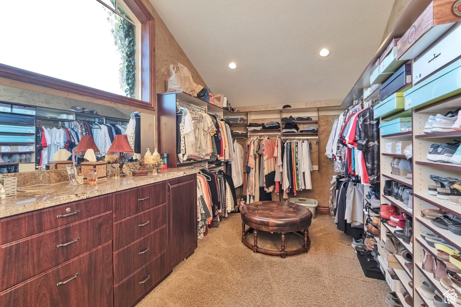 Walk in closet with light carpet and lofted ceiling