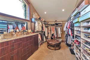 Walk in closet with light carpet and lofted ceiling