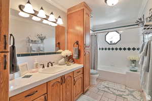 Bathroom featuring vanity, crown molding, shower / tub combo with curtain, tasteful backsplash, and light tile patterned flooring