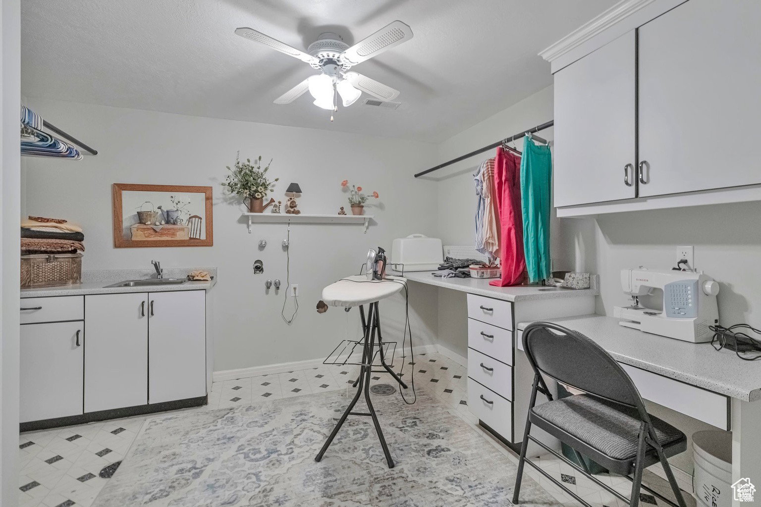 Home office featuring a ceiling fan, light floors, and built in desk