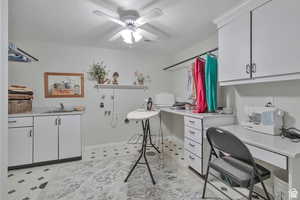 Home office featuring a ceiling fan, light floors, and built in desk