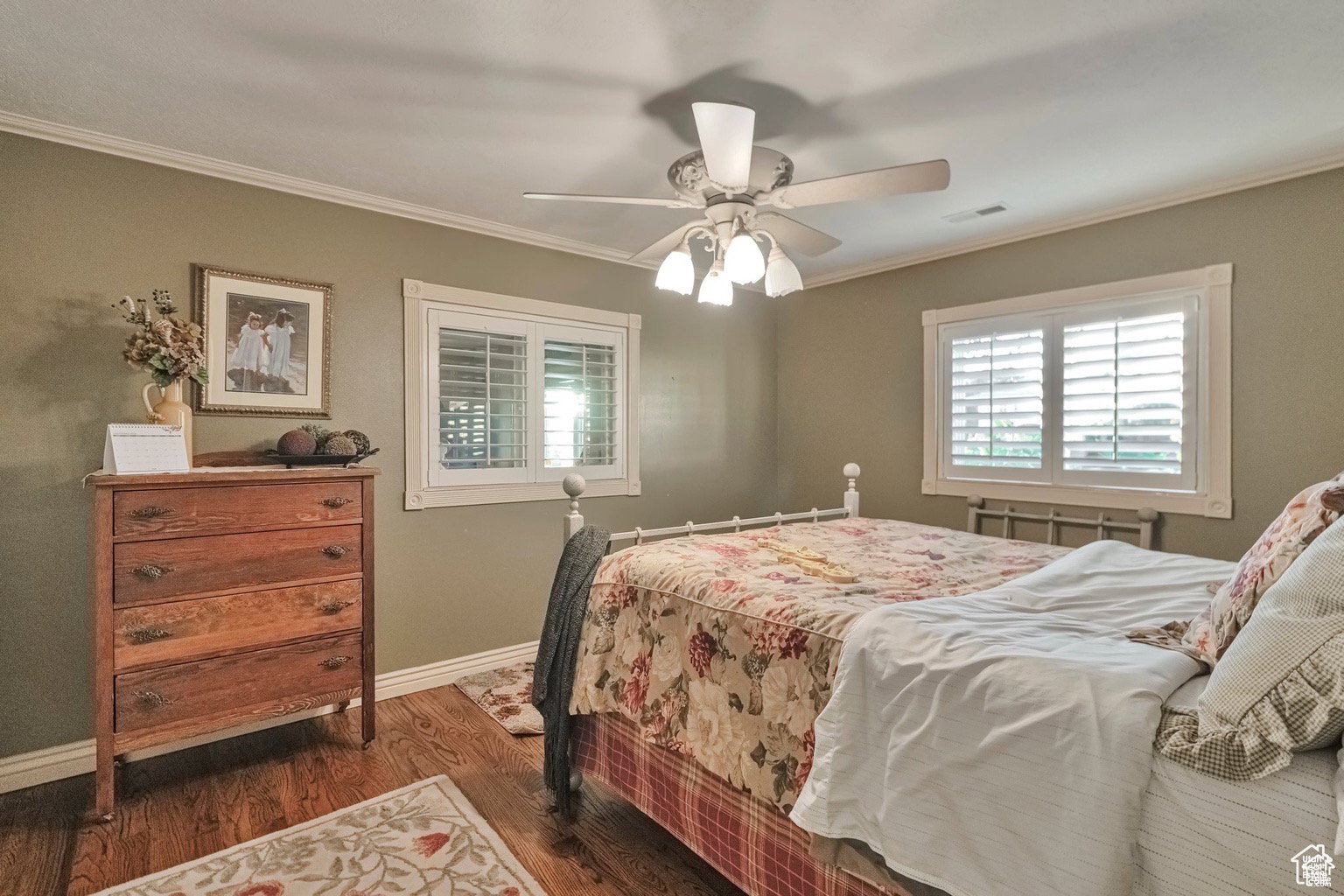 Bedroom with dark wood-style flooring, ornamental molding, and a ceiling fan