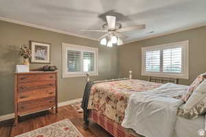 Bedroom with dark wood-style flooring, ornamental molding, and a ceiling fan