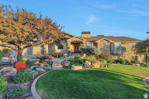 View of front of property featuring a front lawn, a chimney, and stone siding