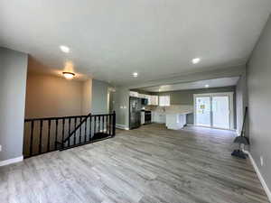 Unfurnished living room featuring light wood finished floors, a textured ceiling, and recessed lighting