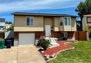Split foyer home with concrete driveway, a garage, and brick siding