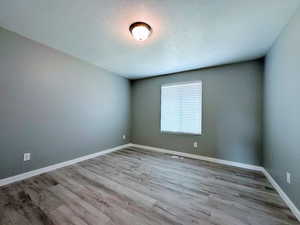 Empty room with a textured ceiling and light wood-type flooring