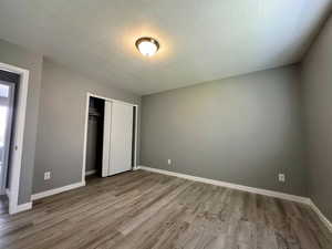 Unfurnished bedroom with a textured ceiling, a closet, and light wood-style flooring