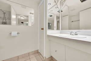 Full bathroom with vanity, light tile patterned floors, and a tile shower
