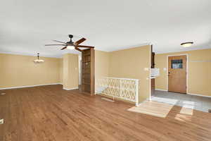 Empty room with ceiling fan, light wood finished floors, a chandelier, crown molding, and a textured ceiling