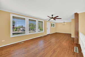Unfurnished room featuring ceiling fan, hanging lights, dark wood-type flooring, and ornamental molding