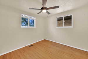 Empty room with light wood-style flooring, ceiling fan, and a textured ceiling