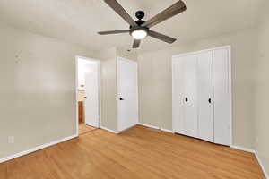 Unfurnished bedroom featuring light wood finished floors, ceiling fan, a textured ceiling, and a closet