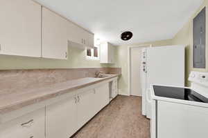 Kitchen with white appliances, white cabinets, a textured ceiling, and tile countertops