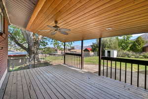 Deck featuring a fenced backyard, ceiling fan, a shed, and a residential view