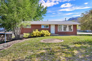 View of front of home featuring brick siding, a front lawn, and a mountain view
