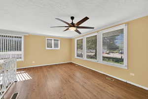 Spare room with dark wood-style floors, a ceiling fan, a textured ceiling, and crown molding