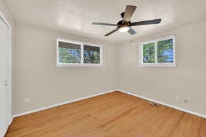 Unfurnished room with light wood-type flooring, plenty of natural light, a textured ceiling, and a ceiling fan
