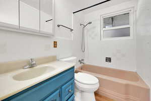 Full bath featuring vanity, tile walls, bathing tub / shower combination, and light wood-style floors
