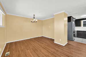 Spare room featuring light wood finished floors, crown molding, a textured ceiling, and suspended lighting