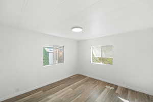 Empty room with wood finished floors and healthy amount of natural light