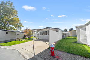 View of front facade featuring a front yard, concrete driveway, and a carport