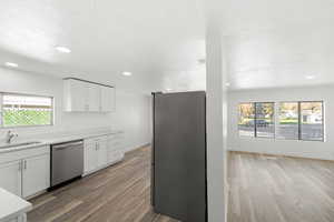 Kitchen with white cabinetry, healthy amount of natural light, stainless steel appliances, light wood-style flooring, and recessed lighting