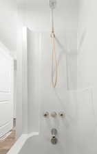 Bathroom view of wood finished floors and shower / bath combination