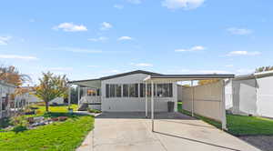 Manufactured / mobile home featuring an attached carport, concrete driveway, and a sunroom