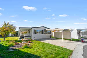 Rear view of house with a yard, an attached carport, concrete driveway, and a porch