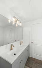 Bathroom featuring double vanity and dark wood-style floors