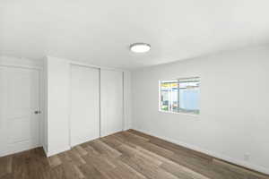 Unfurnished bedroom with a closet, dark wood-style floors, and ornamental molding