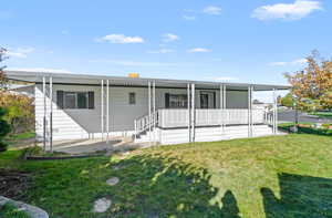 Rear view of house featuring covered porch and a lawn