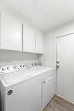 Laundry area with dark wood-type flooring, cabinet space, and washer and dryer