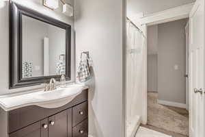 Bathroom featuring a stall shower, vanity, and light carpet
